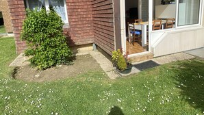 Een huis met een bakstenen gevel, een kleine tuin en een schuifdeur die leidt naar een eethoek.