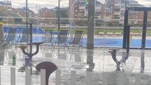 Een natte binnenruimte met uitzicht op een speeltuin en gebouwen.