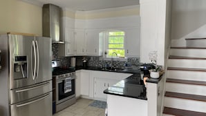 A modern kitchen with stainless steel appliances, white cabinetry, and a black countertop. - Backyard Paradise (Portland)