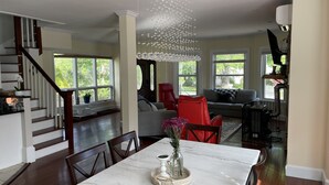 A spacious living area with a dining table, red chairs, and a chandelier. - Backyard Paradise (Portland)