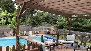A covered outdoor area with a pool, lounge chairs, and a table with potted plants. - Backyard Paradise (Portland)