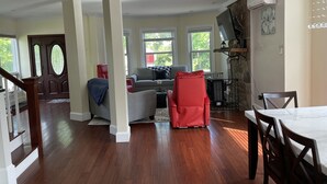 A spacious living room with hardwood floors, a fireplace, and a dining area with a table and chairs. - Backyard Paradise (Portland)