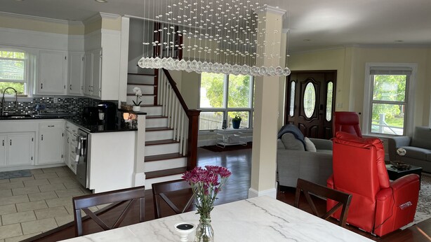 A spacious kitchen with white cabinets, a black countertop, and a modern chandelier. - Backyard Paradise (Portland)