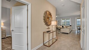 Un vaste espace de vie avec un mur de couleur beige, un miroir décoratif doré et une console en verre.