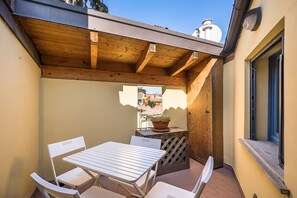 A covered outdoor seating area with a table and chairs, a potted plant, and a view of buildings in the background. - Chez Cristina by Wonderful Italy (Bologna)