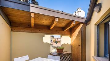 Een patio met een tafel en stoelen, een houten pergola en een uitzicht op gebouwen in de verte.