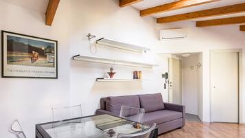 Un soggiorno moderno con un tavolo da pranzo in vetro, un divano viola e un quadro appeso raffigurante un museo.