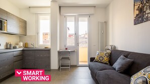 A modern apartment with a kitchen, a dining area, and a living room. There is a balcony with a view of buildings. - Galleria del Reno 2B by Wonderful Italy (Bologna)
