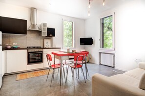 A compact kitchen with a dining area, a built-in oven, and a television mounted on the wall.