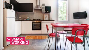 A modern kitchen with a built-in oven, a microwave, and a gas stove. There is a dining area with red chairs and a table.