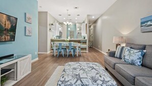 Een moderne woonkamer met een bank, een televisie en een eethoek met stoelen en een tafel.