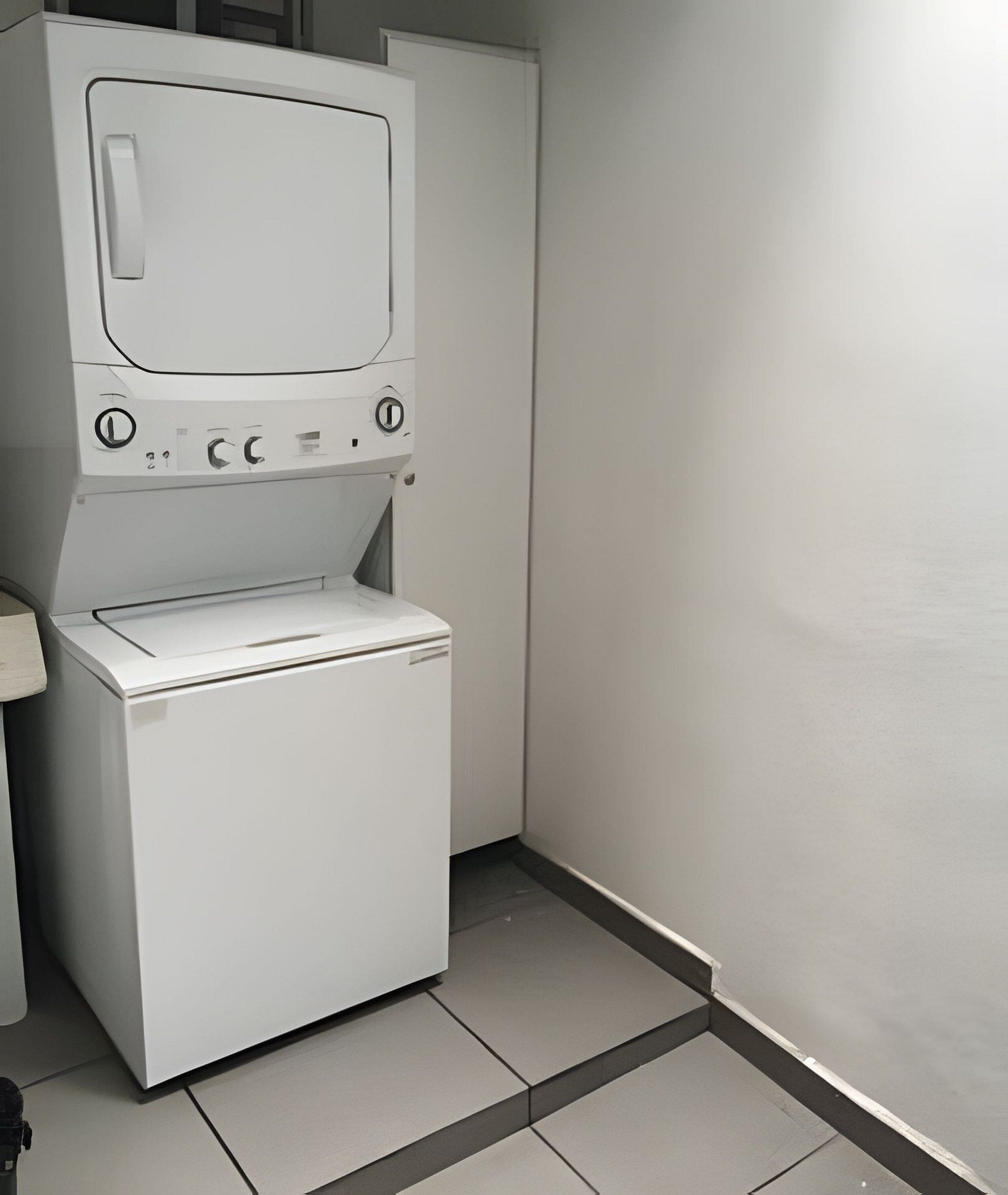 A compact, white laundry room with a washing machine and dryer stacked vertically.