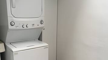 A compact, white laundry room with a washing machine and dryer stacked vertically.
