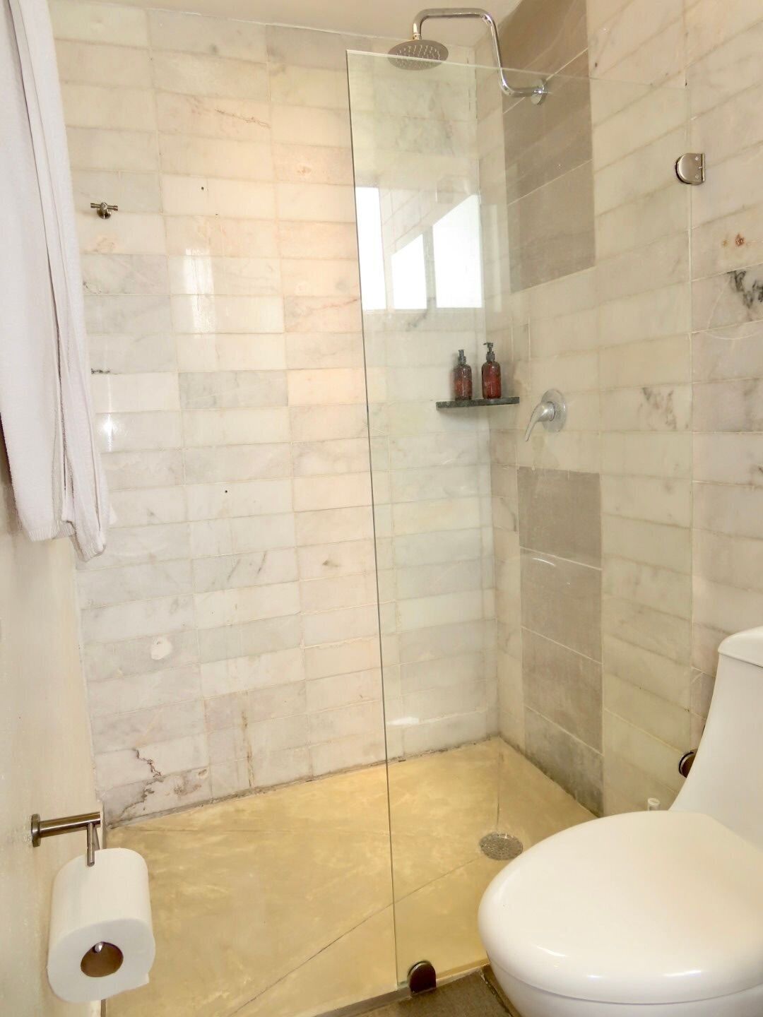 Ein Badezimmer mit Duschkabine, Toilette und Papierhandtuchhalter.