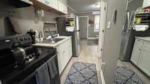 Una cocina moderna con armarios blancos, un refrigerador de acero inoxidable y una alfombra estampada.
