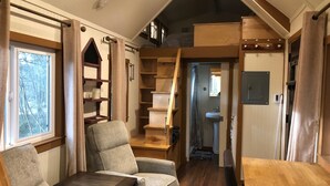 Un intérieur chaleureux avec un coin salon, des étagères en bois et une petite kitchenette.