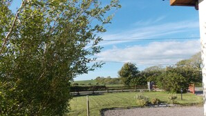 A rural landscape with a gravel path, a wooden fence, and a stone wall. - Charming 1-bed Apartment in Ardfert, Tralee (Ardfert)