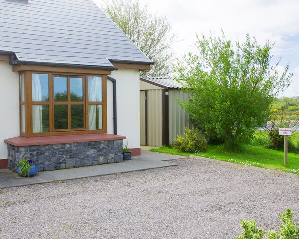 A house with a stone foundation, a red roof, and a large window with wooden frames. - Charming 1-bed Apartment in Ardfert, Tralee (Ardfert)