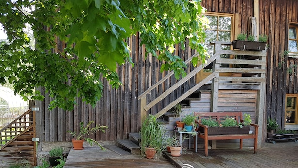 En træterrasse med grill, plantekasser og en træbænk.