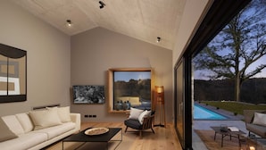 A modern living room with a large window, a sofa, a coffee table, and a floor lamp. - Villa Touch of Nature with Pool (Motovun)