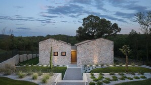 A modern stone house with two main sections, a central door, and a well-maintained garden with gravel paths and greenery. - Villa Touch of Nature with Pool (Motovun)
