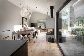 A modern kitchen with a large dining table, a fireplace, and a view of the outdoors. - Villa Touch of Nature with Pool (Motovun)
