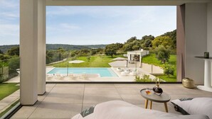 Ein moderner Balkon im Freien mit Pool, Liegestühlen und Blick auf eine üppige Landschaft.