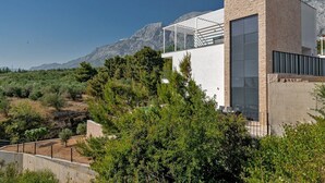 Un edificio moderno con una amplia fachada de vidrio, con montañas al fondo.