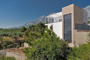 A modern building with a large glass facade, set against a mountainous backdrop.