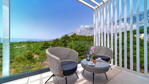 A balcony with wicker chairs and a table, overlooking a mountainous landscape. - Villa Sea Splendor with Pool (Promajna)
