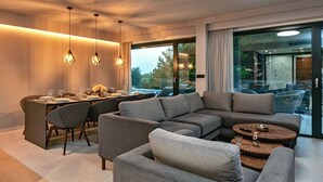 A modern living room with a dining area, grey sofas, and pendant lighting. - Villa Sea Crystal with Pool (Promajna)