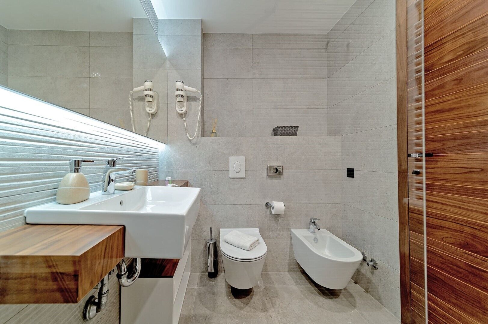 Een moderne badkamer met een ruime wastafel, een bad, een toilet en een douchehoek.