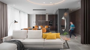 Un salon moderne avec un canapé, un coin repas et une cuisine en arrière-plan.