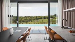 Une cuisine moderne dotée d’une grande fenêtre donnant sur une piscine et un espace verdoyant.