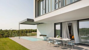 Une maison moderne dotée d’une piscine, d’un espace salon extérieur et de grandes fenêtres.