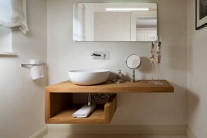 A modern bathroom with a wooden vanity, a large white sink, a mirror, and a towel rack.