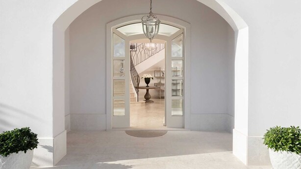 An arched doorway leading to a staircase with a chandelier, surrounded by white walls and potted plants. - Villa Palazzo di Claretta with Pool (Vabriga)