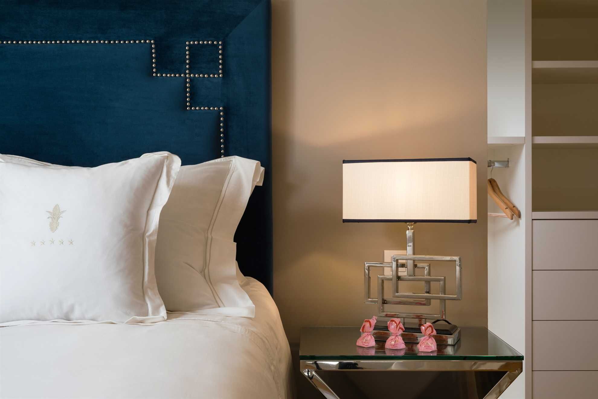 Habitación de hotel con una cama, una mesita de noche con lámpara y un espejo.