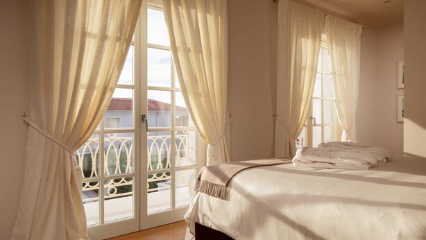 A bedroom with a bed, curtains, and a view through a glass door. - Villa Palazzo di Letizia with Pool (Vabriga)