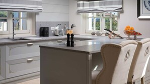 A modern kitchen with a central island, white cabinetry, and a view of the outdoors through large windows. - Villa Palazzo di Letizia with Pool (Vabriga)