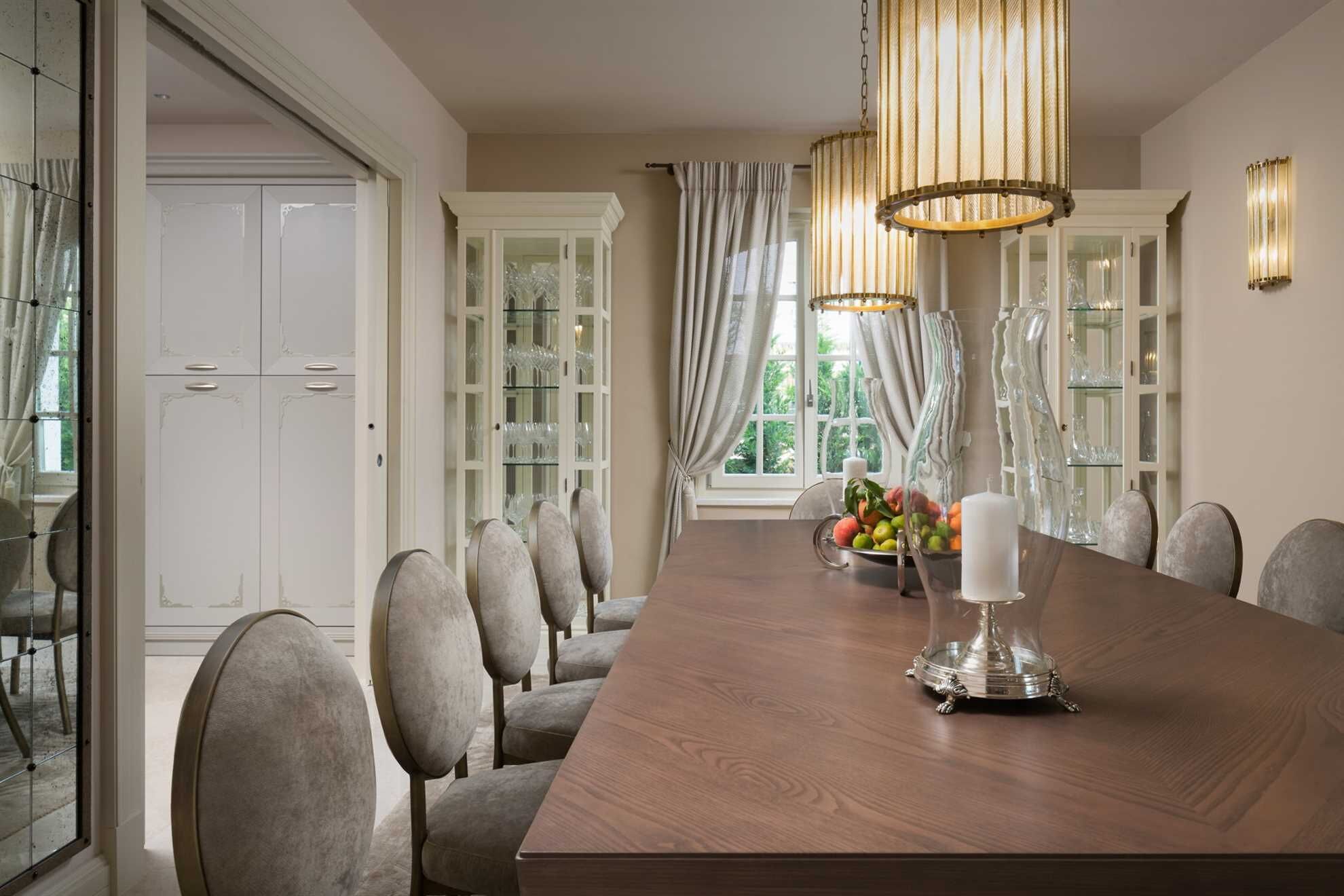 A dining room with a long wooden table, six chairs, and a chandelier.