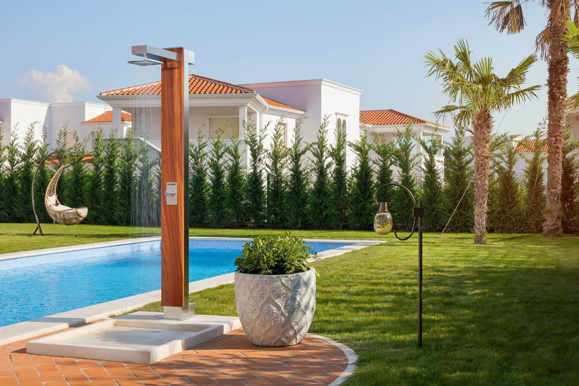 A swimming pool with a wooden structure, a hanging chair, and a large decorative planter.