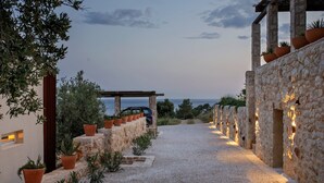 A gravel pathway leading to a stone structure with terracotta pots and plants.