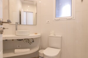 Een badkamer met een wit wastafel, spiegel en toilet.