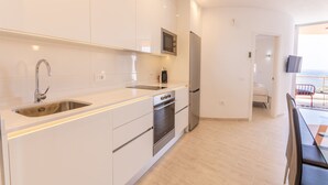 Een moderne keuken met witte kasten, roestvrijstalen apparatuur en een ingebouwde magnetron.