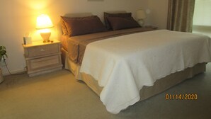 A neatly made bed with a white comforter, a bedside lamp, and a nightstand with a lamp. - Golf club Villa located in beautiful Naples , 5 min from Beaches and Downtown (naples)
