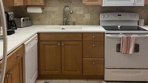 A kitchen with wooden cabinets, a white microwave, a stove, a sink, and a ceiling fan. - Golf club Villa located in beautiful Naples , 5 min from Beaches and Downtown (naples)