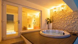 A spa area with a hot tub, stone wall, and a view of a bathroom. - Villa Simpleza - Six Bedroom Villa with Private Pool and Jacuzzi (Klek)