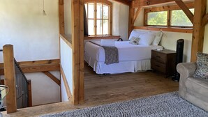 Une chambre dans une cabane en bois, avec un lit, une table de chevet et une fenêtre.