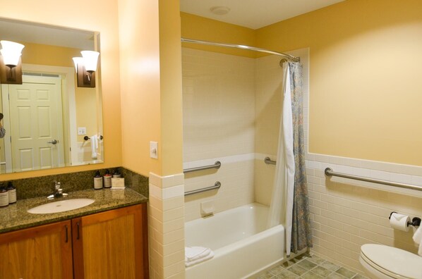 A bathroom with a sink, mirror, shower, and toilet.